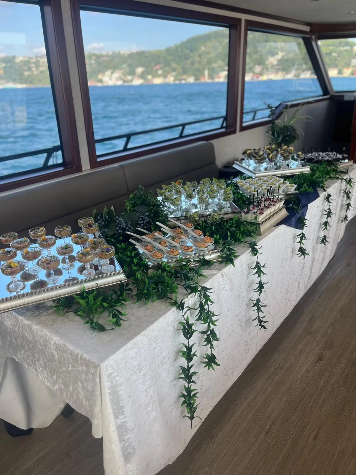 Boğaz manzaralı tekne davetinde yeşillik dekorlu kokteyl büfesi